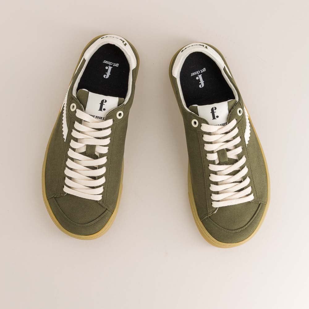 Pair of green barefoot sneakers with white laces on a light gray background