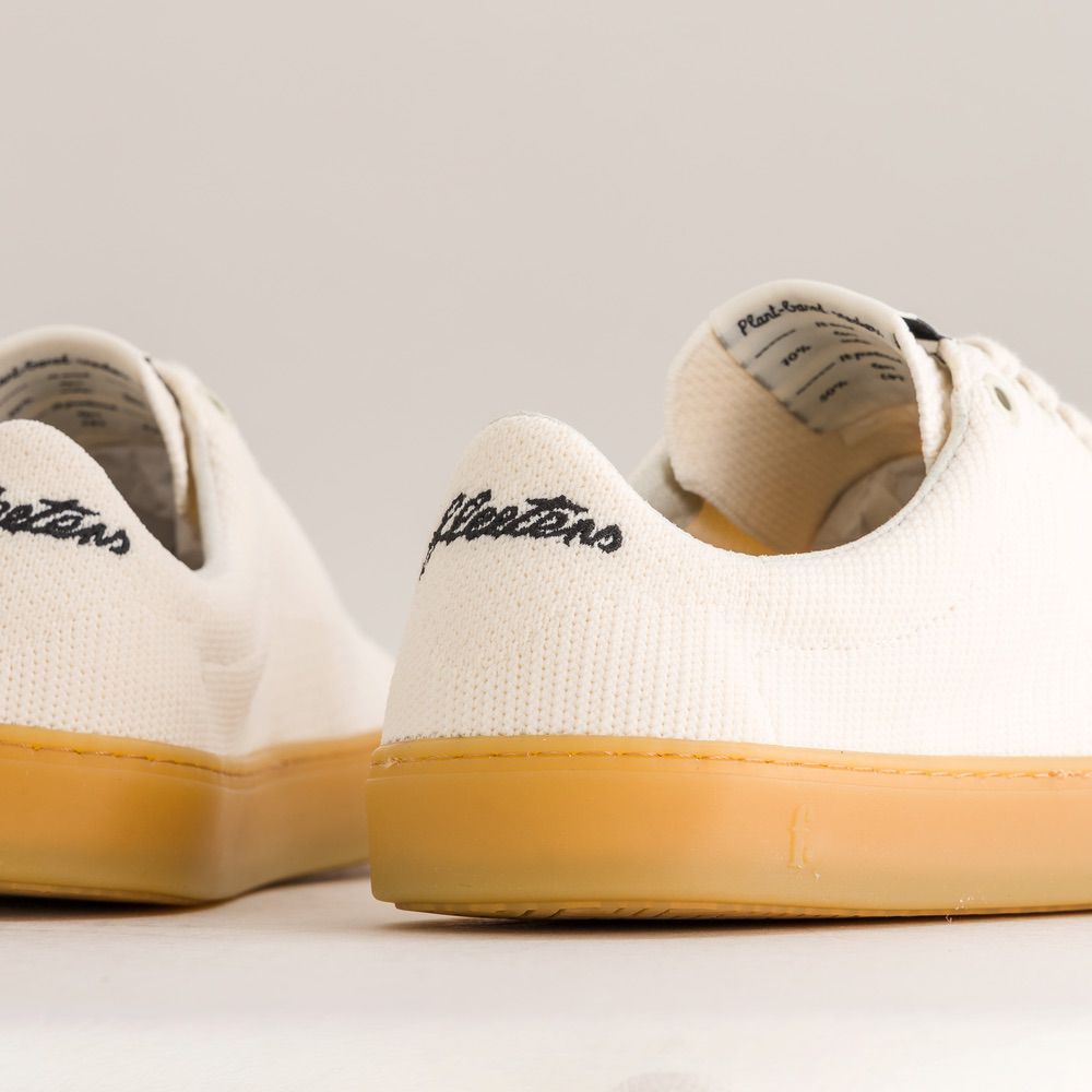 White knit barefoot sneakers with yellow soles on a light gray background
