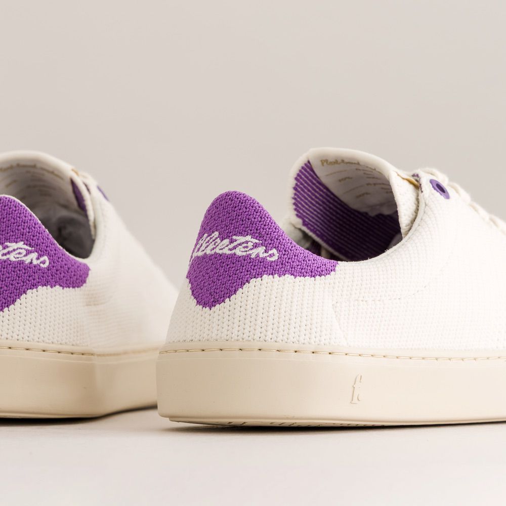 White knit barefoot sneakers with purple accents on a light gray background