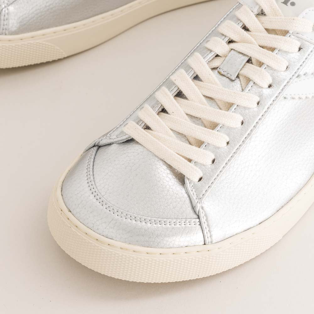 Close-up of silver sneakers with white laces on a light background