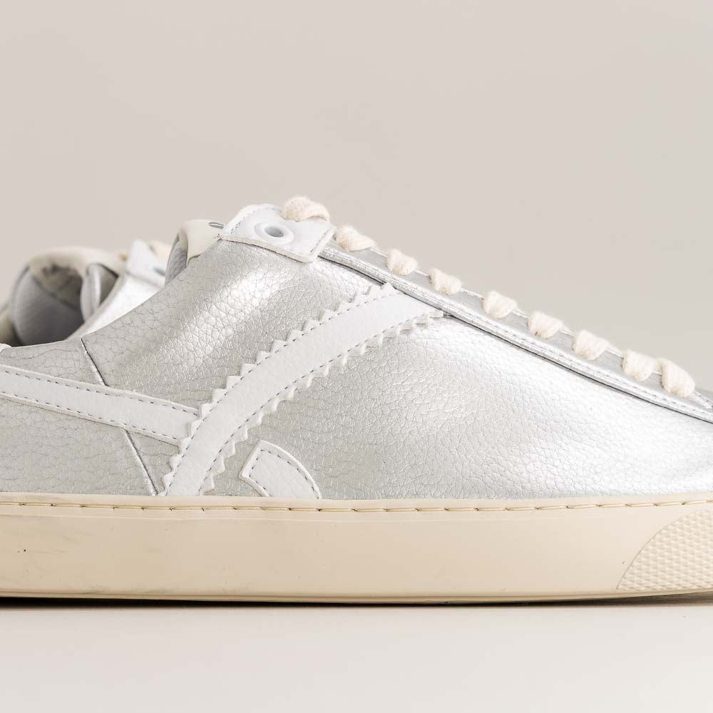 Silver barefoot sneaker with white laces on a light gray background