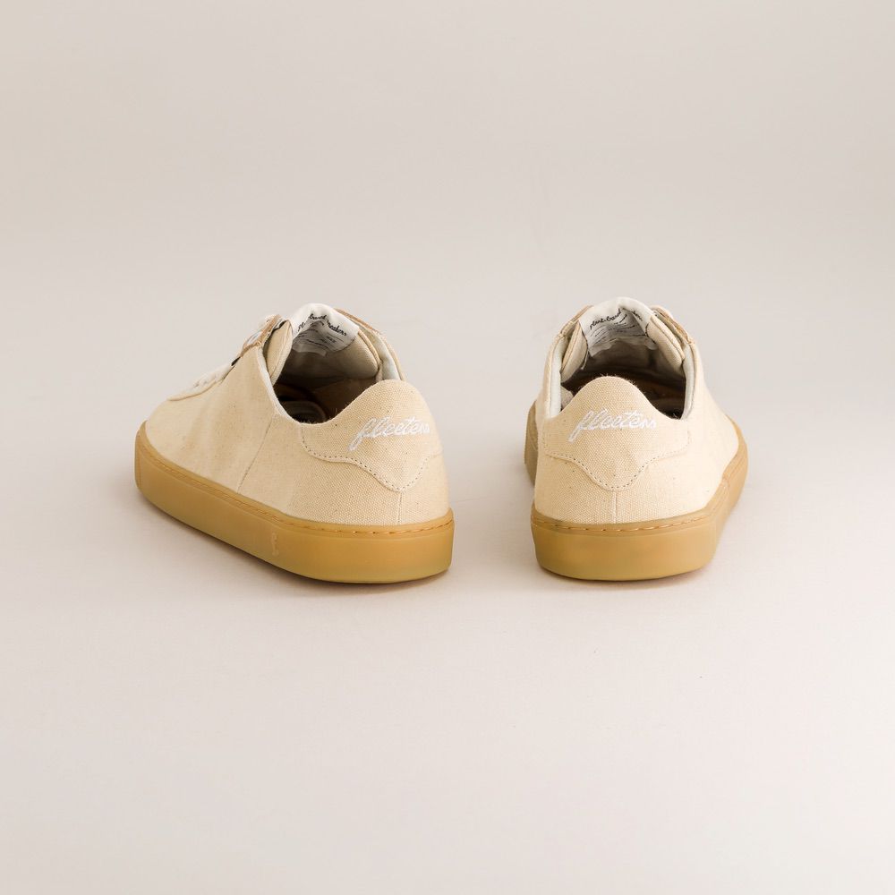 Pair of beige barefoot sneakers with brown soles on a light gray background