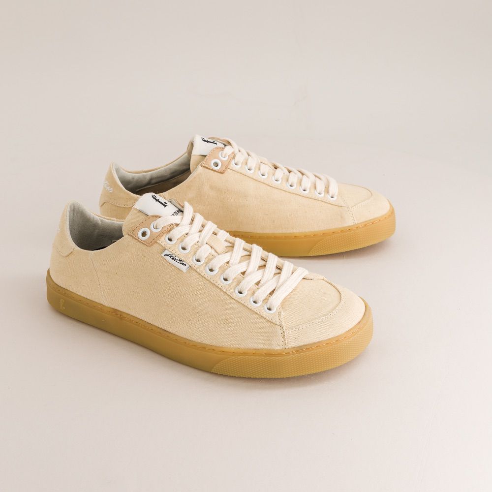 Beige barefoot sneakers with white laces on a light gray background
