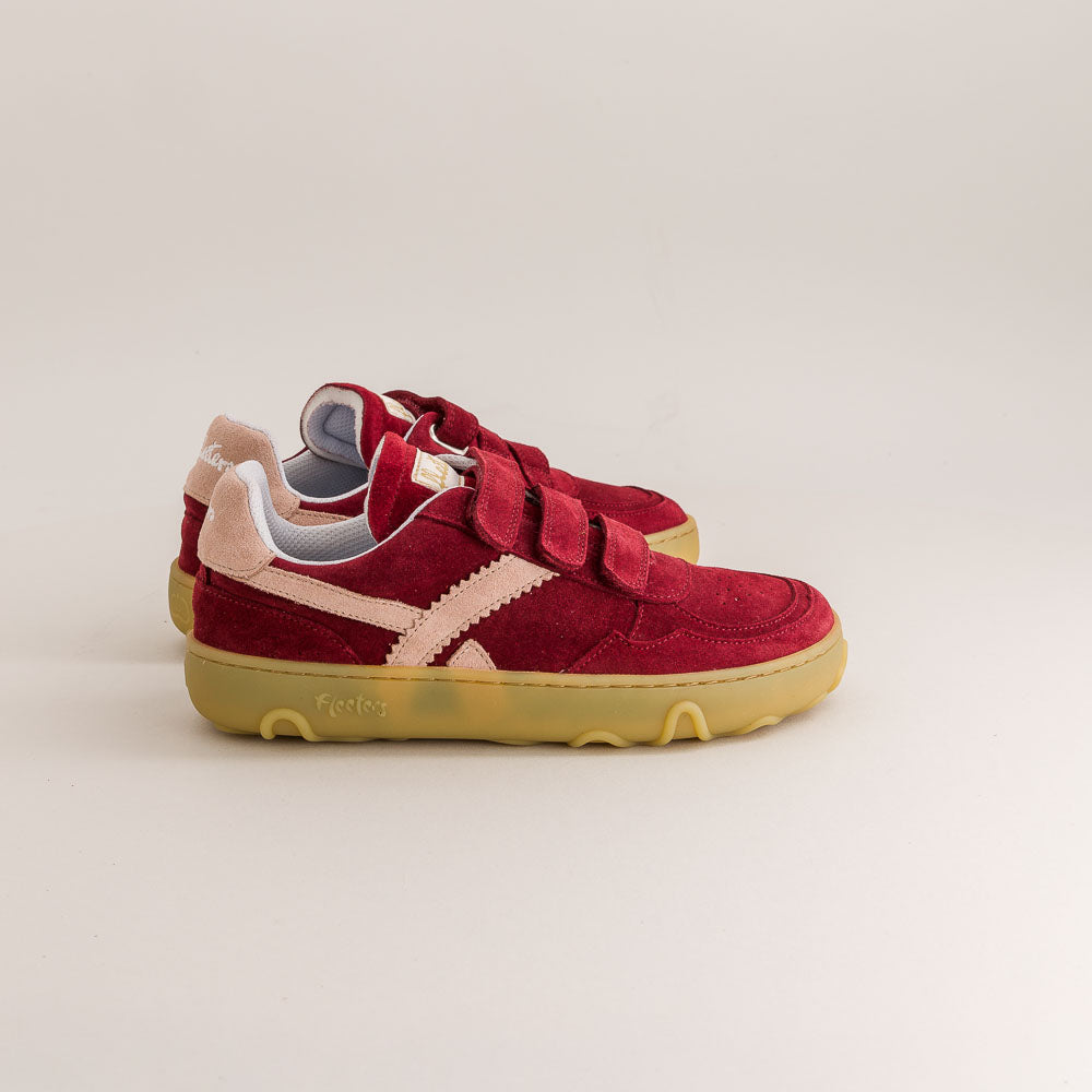 Red children's barefoot sneakers with yellow soles on a beige background