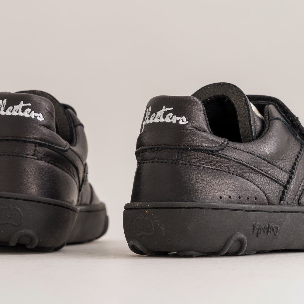 Black kids barefoot sneakers with 'Fleeters' branding on a light gray background