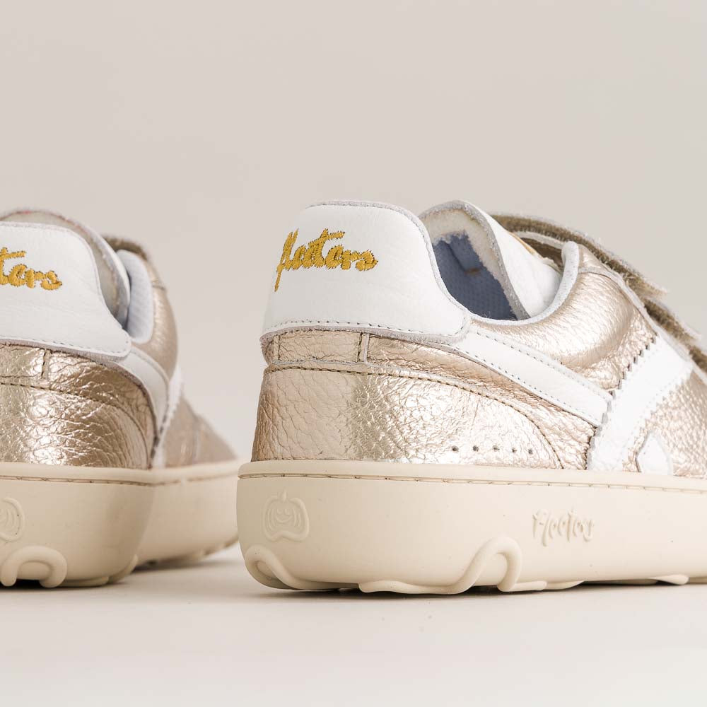 Pair of gold and white kids barefoot sneakers with 'Fleeters' branding on a light background