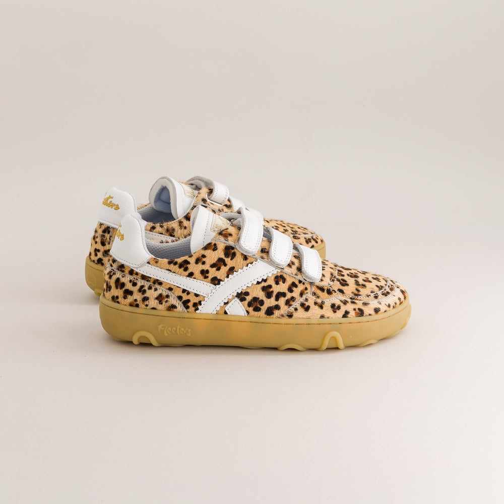 A pair of children's barefoot sneakers with a beige and black leopard print upper, white straps, and a tan sole, shown on a light beige background.