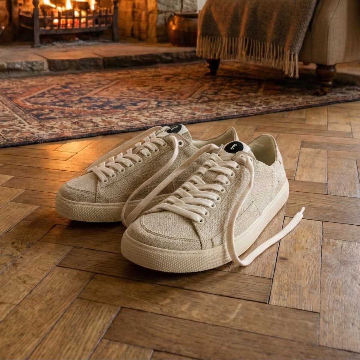 Pair of beige wool barefoot sneakers on a wooden floor with a cozy room background