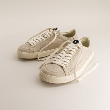 Pair of beige barefoot sneakers in wool with white laces on a light background