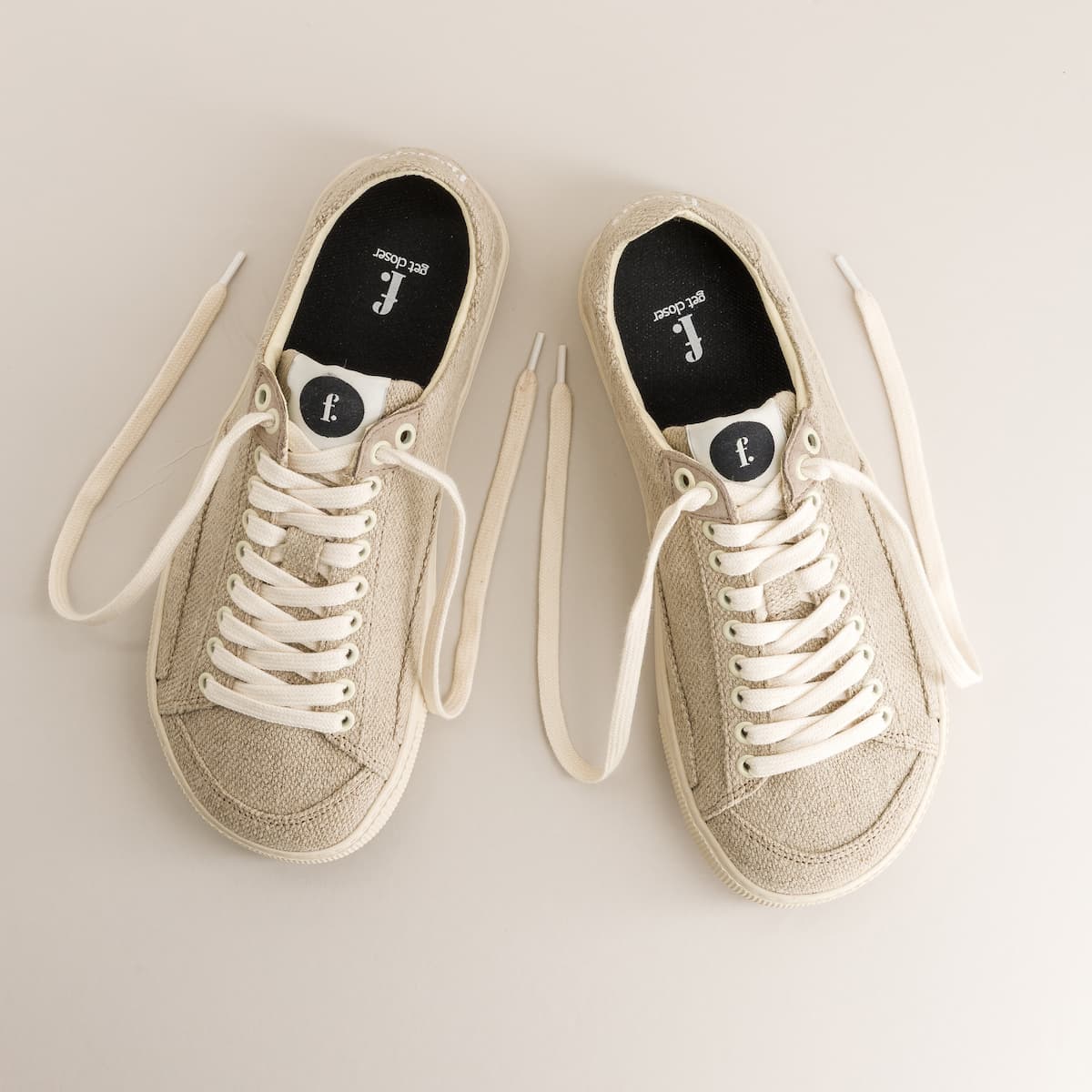 Pair of beige barefoot sneakers in wool with white laces on a light gray background