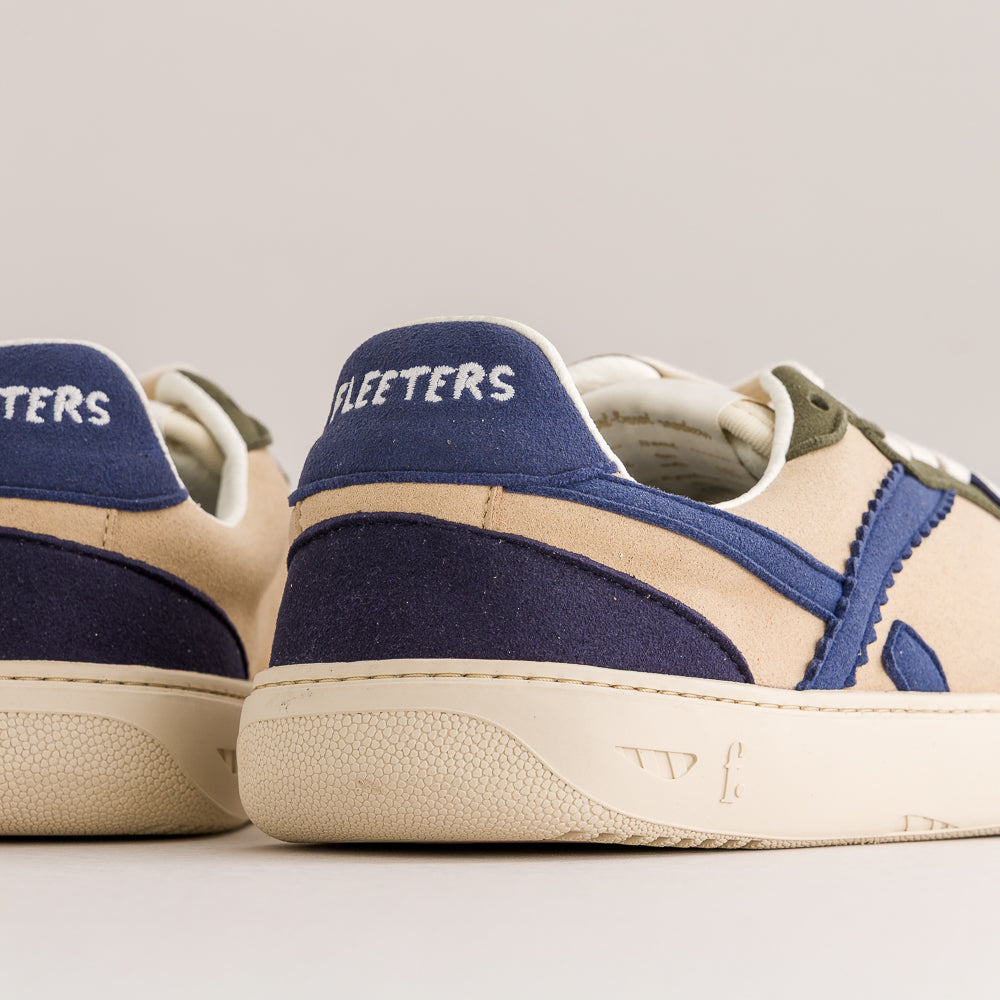 Close-up rear view of a pair of Fleeters low-top sneakers in beige suede and navy blue canvas, with white lettering on the heel tabs and off-white soles.
