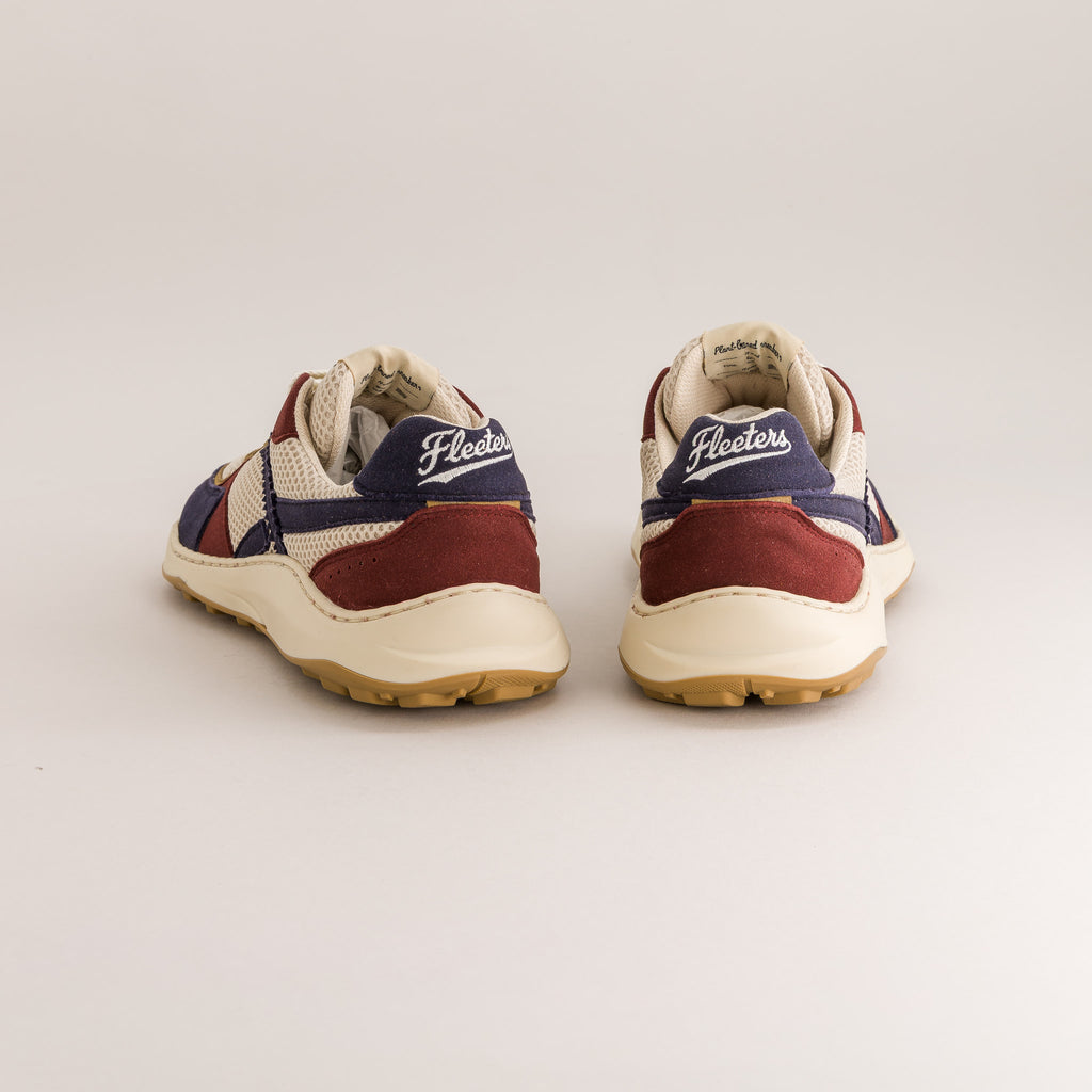 A pair of Fleeters brand low-top barefoot sneakers shown from the back, featuring cream mesh and suede panels, burgundy suede overlays, navy blue heel accents with white script, and a gum rubber sole, set against a plain light gray background.