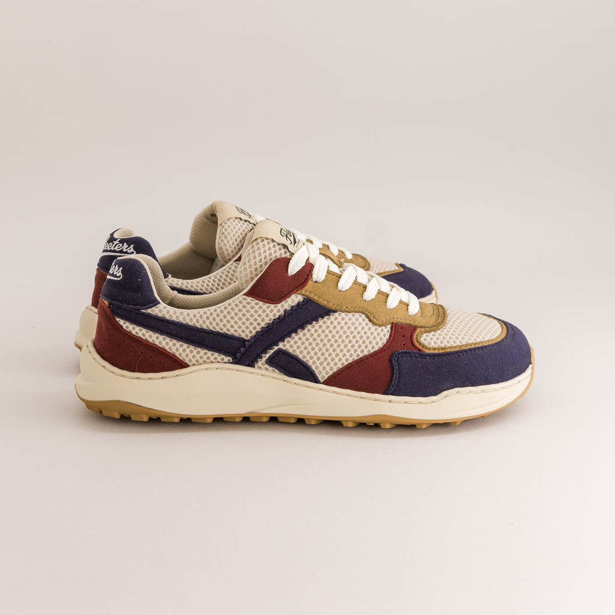 A pair of vintage-style retro barefoot sneakers in a cream, navy blue, burgundy, and tan colorway, shown from a side profile on a light gray background.