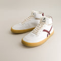 White high-top barefoot sneakers with maroon accents on a beige background