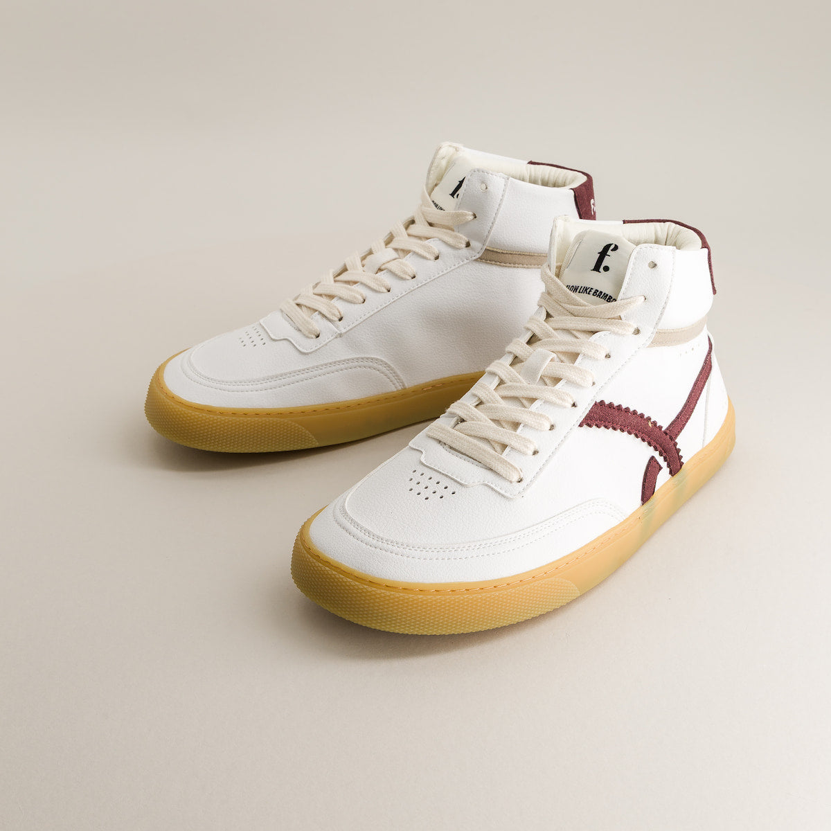White high-top barefoot sneakers with maroon accents on a beige background