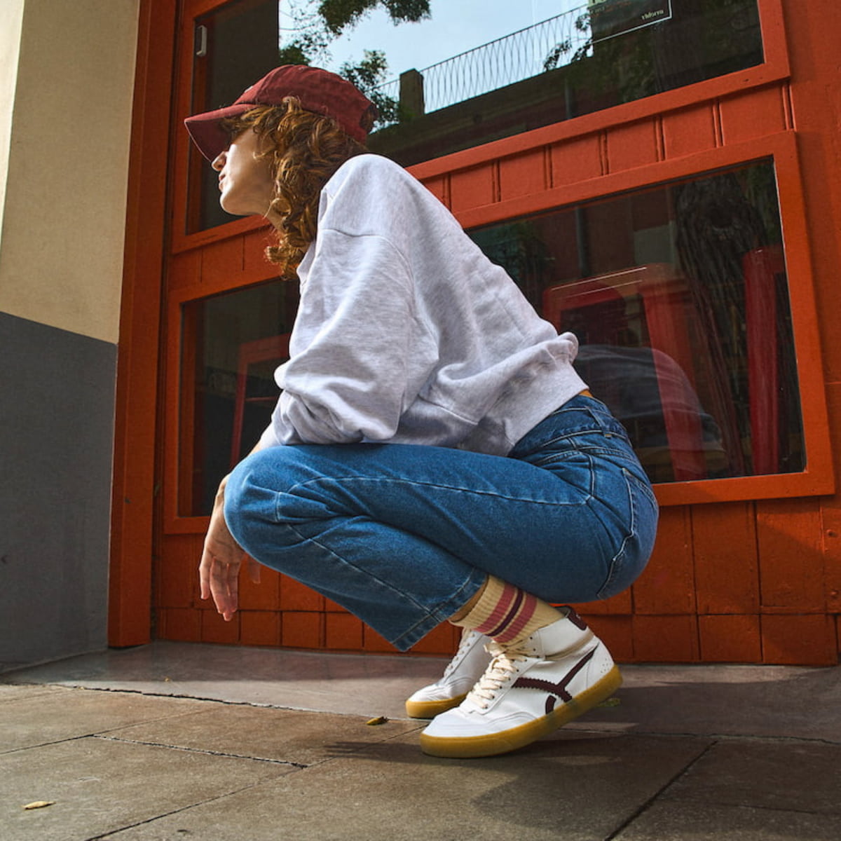 girl wearing white barefoot sneaker mid top with yellow sole on a beige