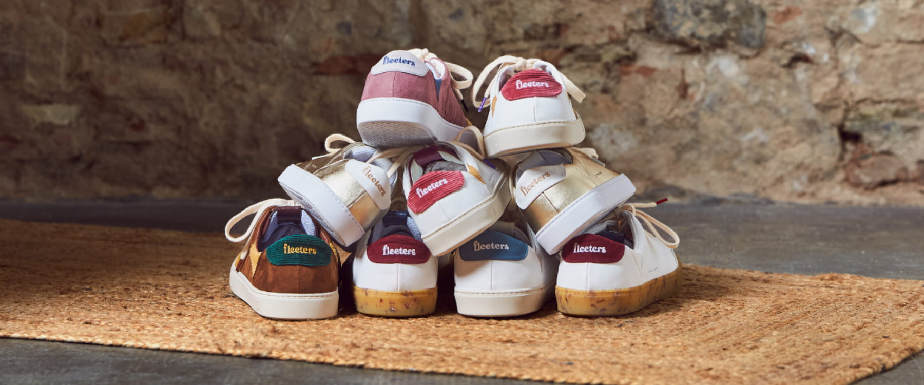 Set of barefoot sneakers on a doormat against a stone wall background