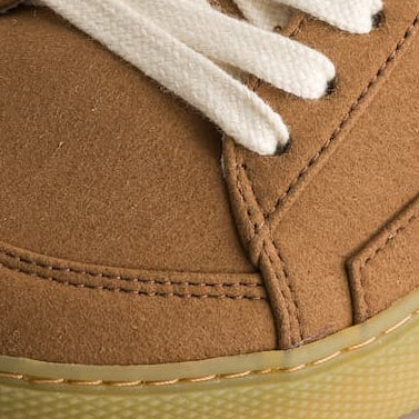 Brown minimalist sneakers with white laces on a light background